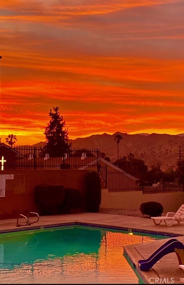 pool at dusk featuring a mountain view and a patio