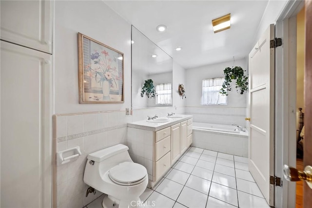 bathroom with toilet, tile walls, vanity, tiled tub, and tile patterned flooring