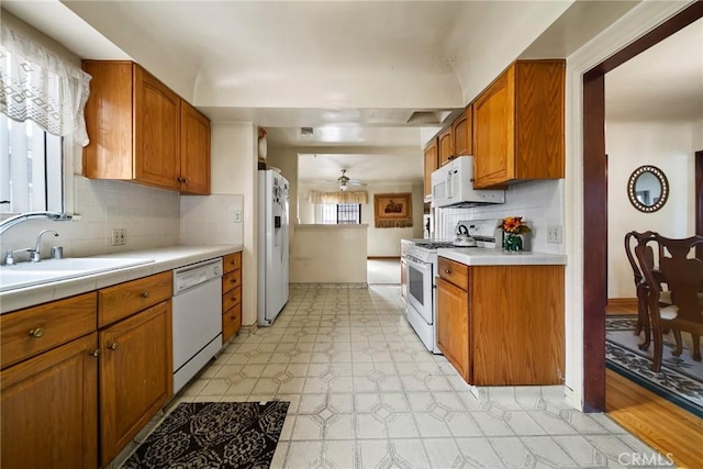 kitchen featuring ceiling fan, white appliances, sink, and backsplash