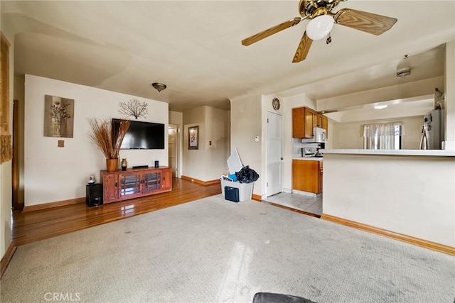 unfurnished living room with light colored carpet and ceiling fan