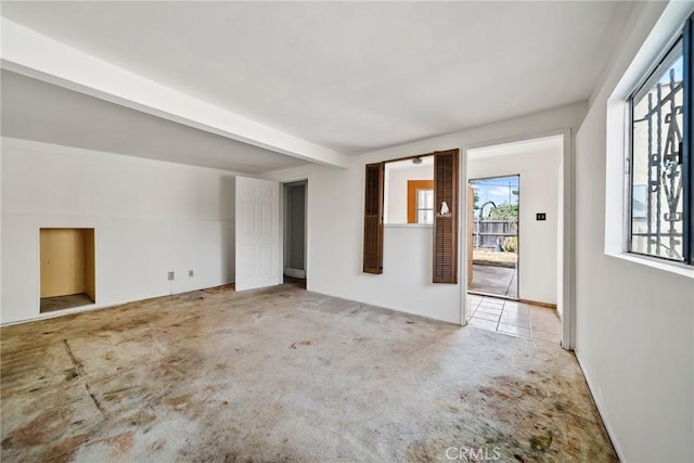 carpeted spare room featuring beamed ceiling