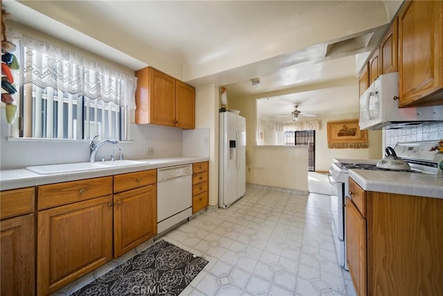 kitchen featuring sink, white appliances, tile counters, ceiling fan, and backsplash