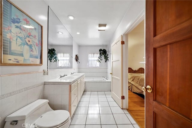 bathroom featuring tile patterned floors, toilet, tile walls, vanity, and a relaxing tiled tub