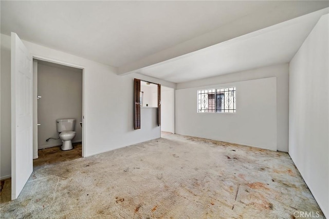 unfurnished bedroom featuring light carpet and ensuite bath