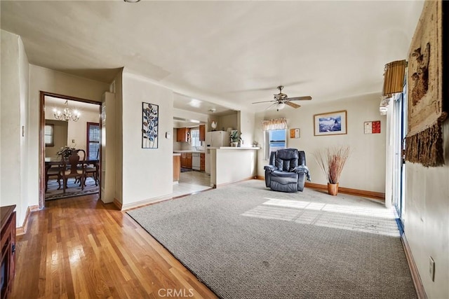 unfurnished living room featuring ceiling fan with notable chandelier and light hardwood / wood-style floors