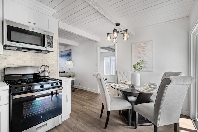 kitchen with pendant lighting, tasteful backsplash, beamed ceiling, white cabinets, and stainless steel appliances