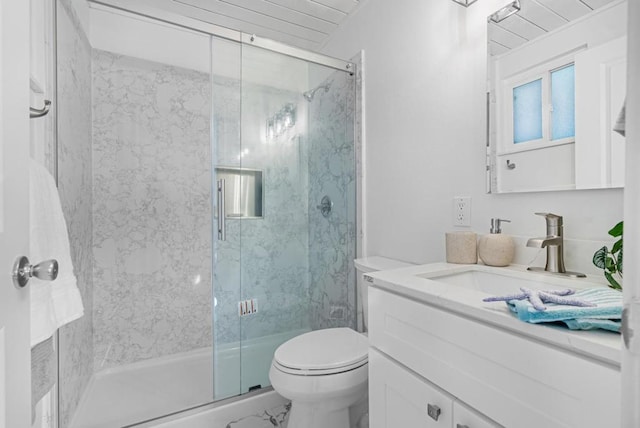 bathroom featuring vanity, a shower with shower door, and toilet