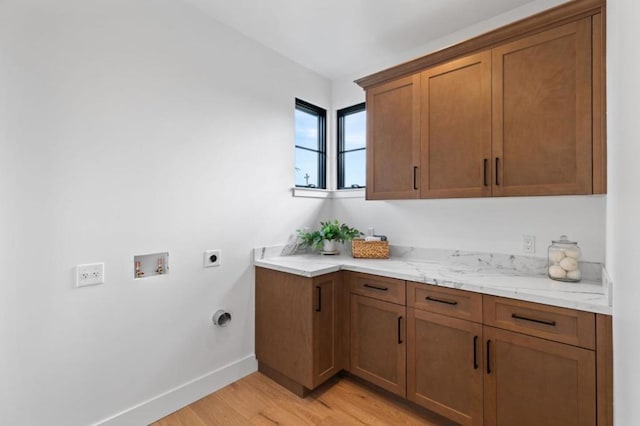 washroom featuring electric dryer hookup, washer hookup, light hardwood / wood-style floors, and cabinets