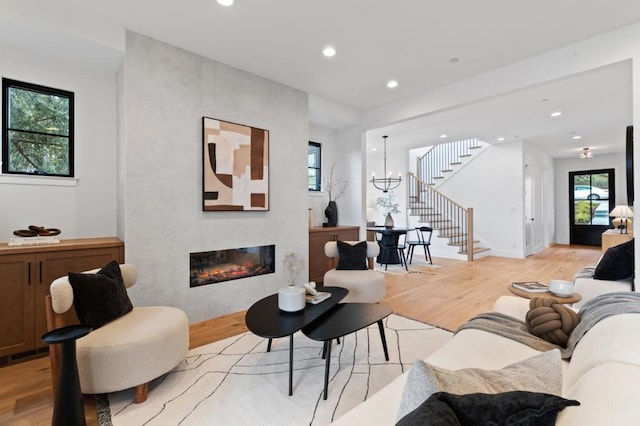 living room featuring a fireplace, light hardwood / wood-style flooring, and a chandelier