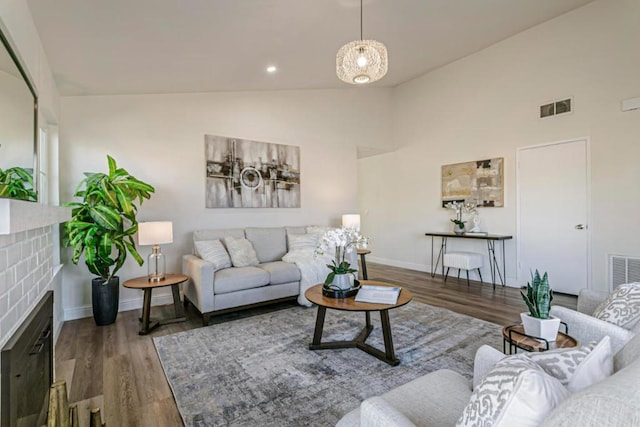 living room featuring lofted ceiling, dark hardwood / wood-style floors, and a brick fireplace