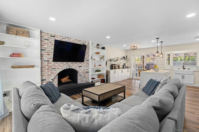 living room featuring sink, hardwood / wood-style flooring, and a brick fireplace