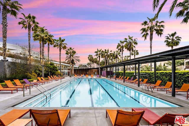 pool at dusk featuring a patio area