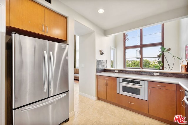 kitchen featuring light tile patterned flooring, appliances with stainless steel finishes, and decorative backsplash