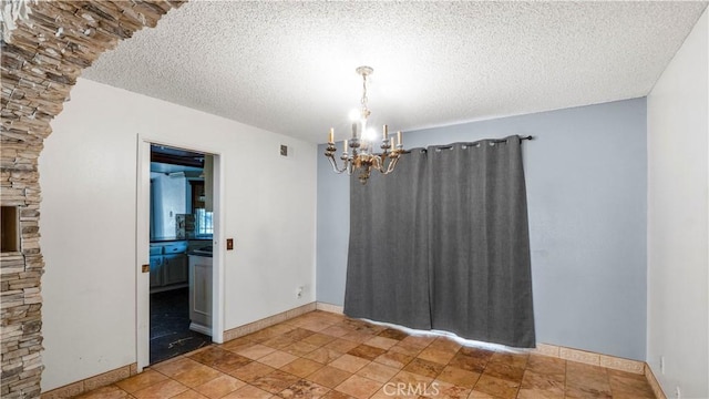 unfurnished room with a textured ceiling, a chandelier, visible vents, and baseboards