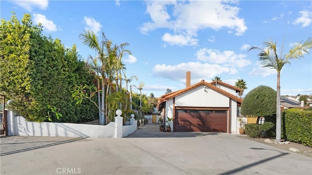 view of front of property with a garage, concrete driveway, and fence