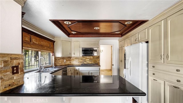 kitchen with stainless steel appliances, cream cabinets, a peninsula, and a sink