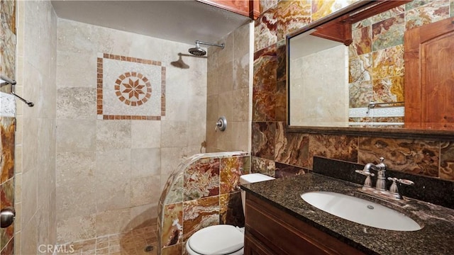 full bathroom with tiled shower, toilet, backsplash, vanity, and tile walls