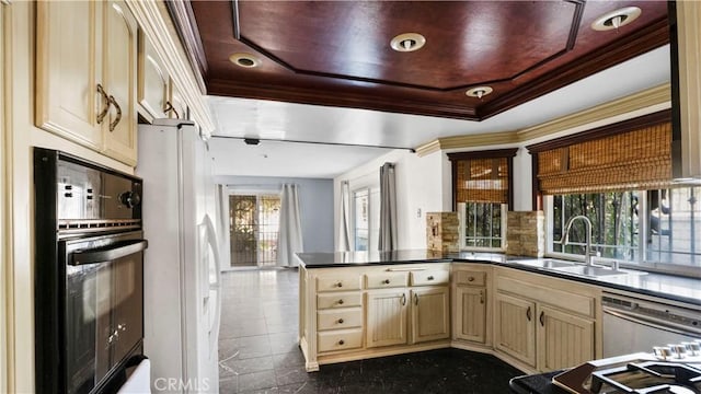 kitchen featuring dishwasher, oven, a peninsula, cream cabinets, and a sink