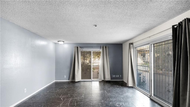 unfurnished room with baseboards and a textured ceiling