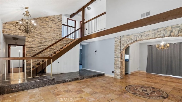 unfurnished living room featuring arched walkways, stairway, visible vents, and a notable chandelier