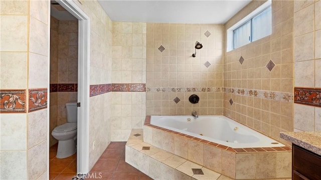 full bath with tile walls, toilet, vanity, tile patterned flooring, and a bath