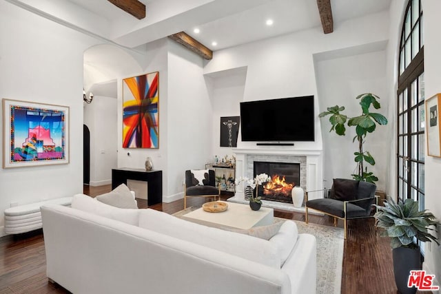 living room with a towering ceiling, dark wood-type flooring, and beamed ceiling