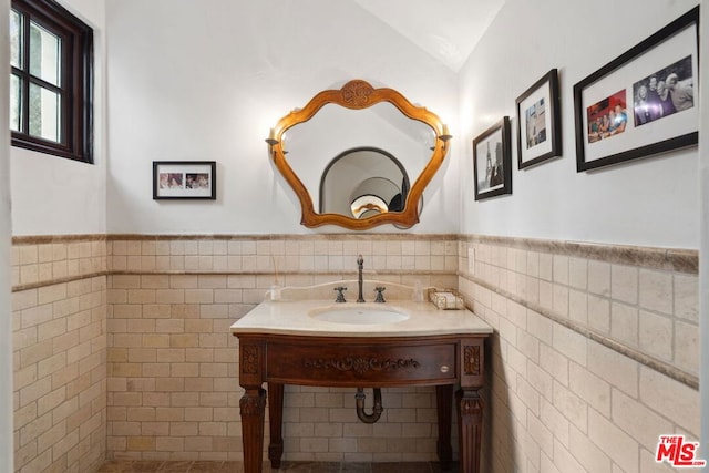 bathroom with lofted ceiling, tile walls, and vanity