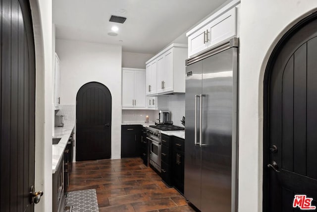 kitchen featuring white cabinetry, premium appliances, backsplash, and dark hardwood / wood-style floors