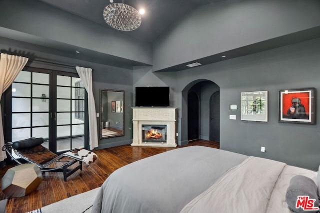 bedroom with french doors, a towering ceiling, and hardwood / wood-style flooring