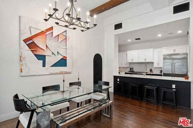 dining area with sink, a notable chandelier, dark hardwood / wood-style floors, and beamed ceiling