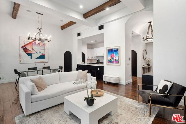 living room featuring hardwood / wood-style flooring, sink, a notable chandelier, and beamed ceiling