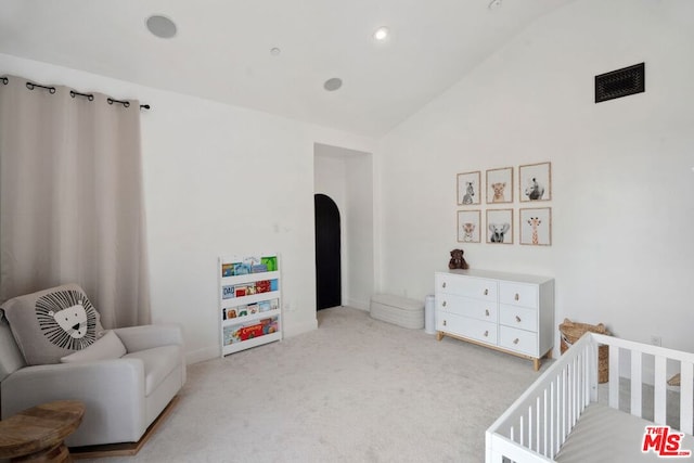 carpeted bedroom featuring a nursery area and vaulted ceiling