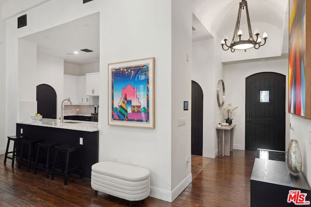 entrance foyer featuring sink, dark wood-type flooring, and a notable chandelier