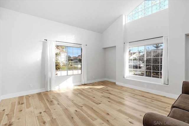 unfurnished living room featuring high vaulted ceiling and light hardwood / wood-style floors