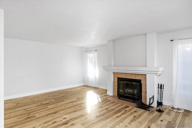 unfurnished living room with wood-type flooring and a tile fireplace