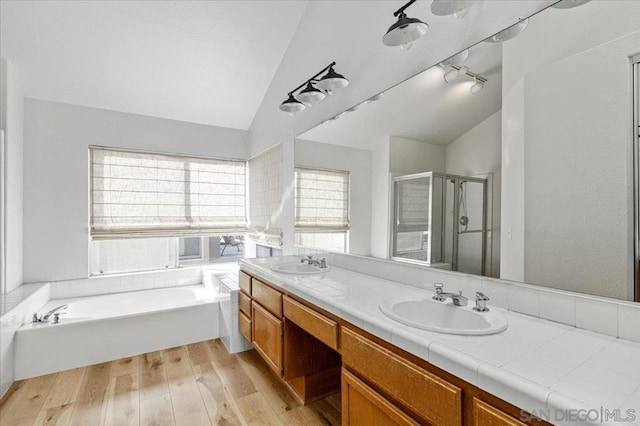 bathroom featuring lofted ceiling, vanity, wood-type flooring, and shower with separate bathtub