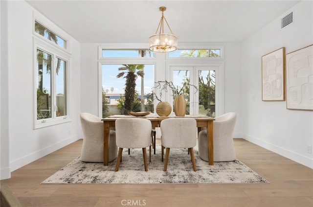 dining space with baseboards, wood finished floors, visible vents, and a notable chandelier