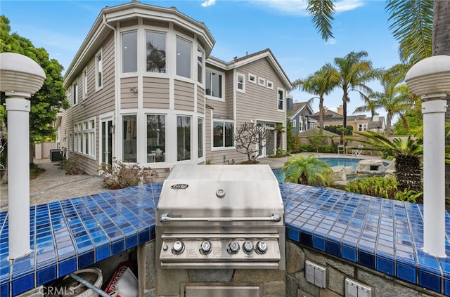 rear view of house featuring a patio area, a fenced in pool, and exterior kitchen