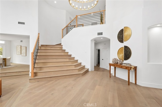 foyer entrance with arched walkways, stairway, wood finished floors, and visible vents