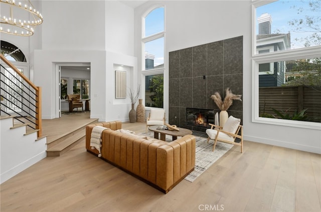 living room featuring an inviting chandelier, stairs, wood finished floors, and a tiled fireplace