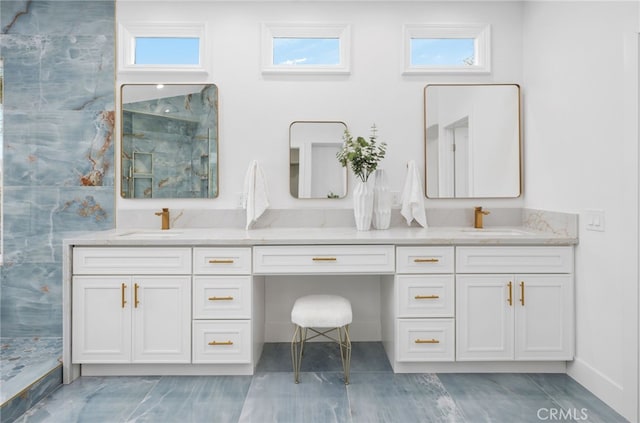 full bath featuring plenty of natural light, a sink, a marble finish shower, and double vanity