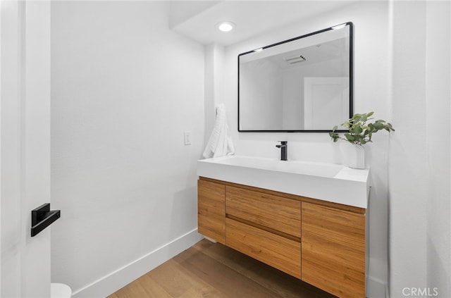 bathroom featuring visible vents, vanity, baseboards, and wood finished floors