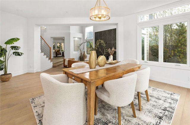 dining space with light wood-style floors, baseboards, stairway, and a chandelier