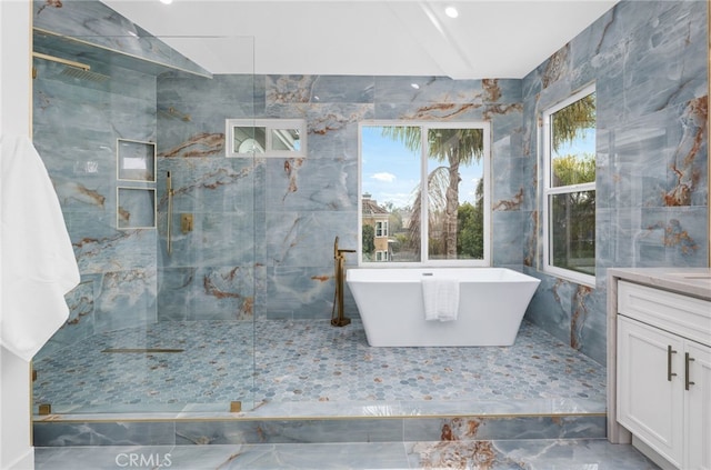 bathroom featuring a soaking tub, a marble finish shower, and vanity