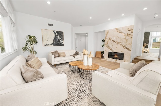 living area featuring a premium fireplace, visible vents, and recessed lighting