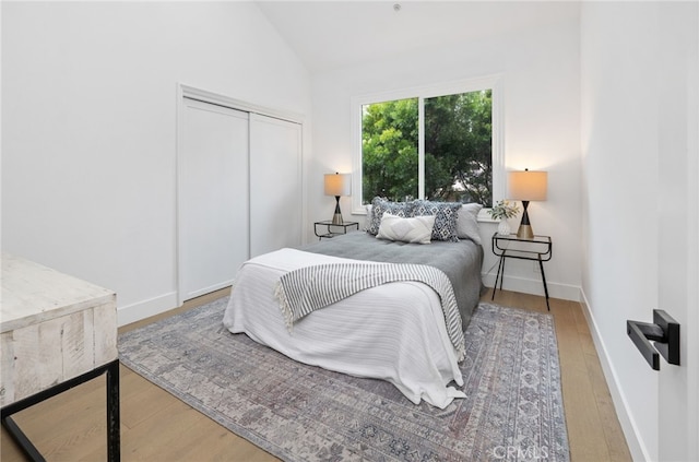 bedroom featuring a closet, baseboards, vaulted ceiling, and wood finished floors