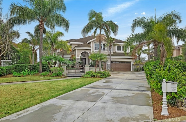 view of front of property featuring concrete driveway, a front lawn, an attached garage, and fence