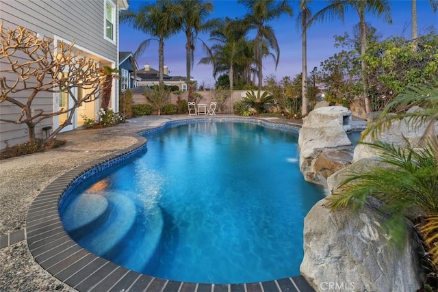 pool at dusk with a fenced backyard and an outdoor pool