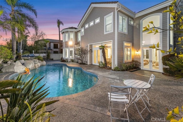 rear view of property with french doors, a patio area, and an outdoor pool