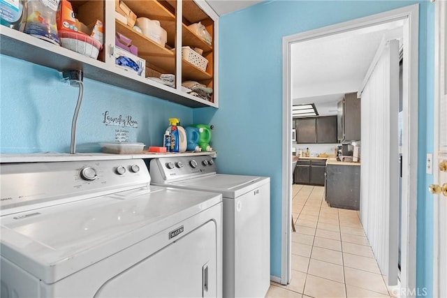 clothes washing area with light tile patterned floors and washer and clothes dryer